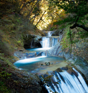 Enchanting autumn scene of Nishizawa Valley with waterfalls, foliage, and serene atmosphere in Japan.