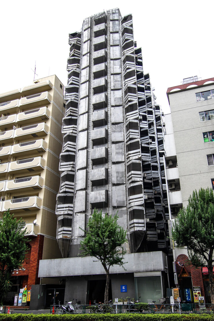 Innovative high-rise building in Shinjuku with stacked, angular glass and concrete elements.