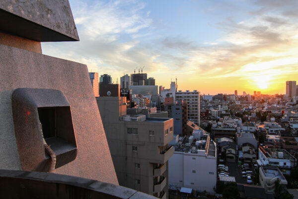 Sunset cityscape in Shinjuku with iconic New Sky Building amidst vibrant urban glow.