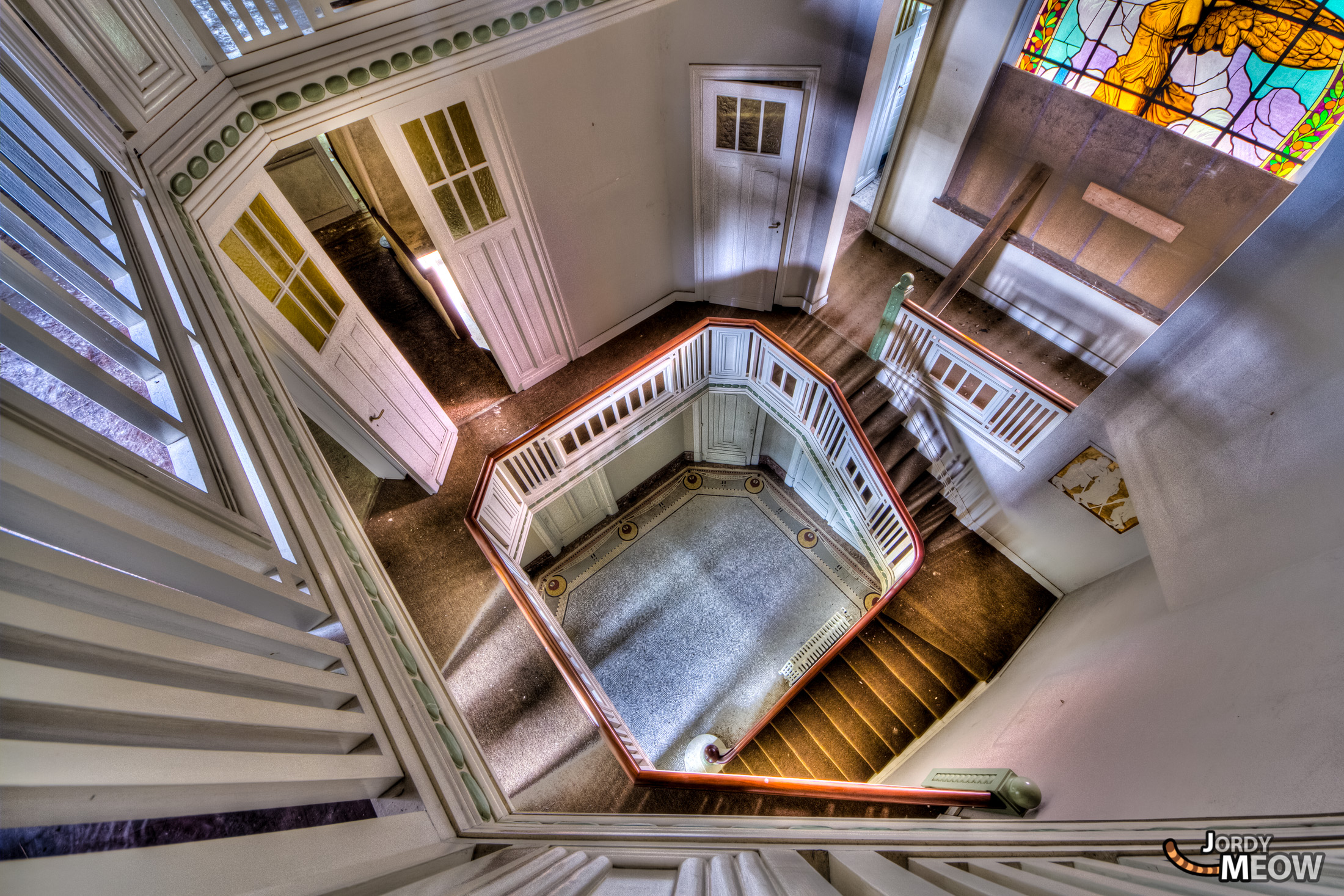 Decaying elegance: Abandoned villa staircase in Belgium, showcasing bygone opulence and neglect.