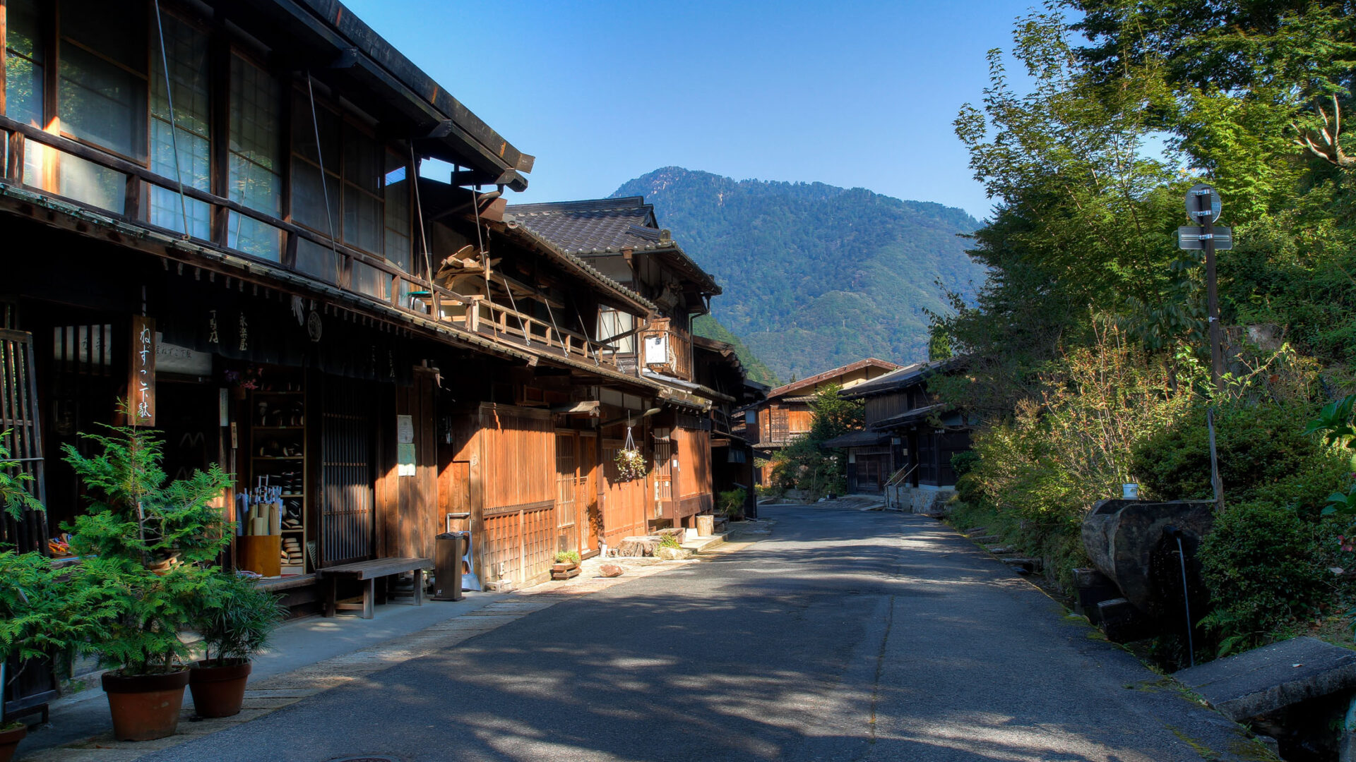 Tranquil Japanese village with traditional wooden buildings nestled in lush green mountains.