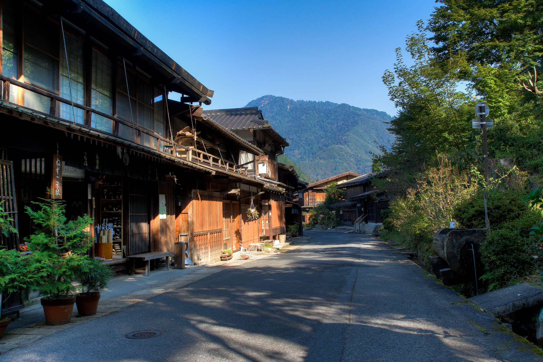 Tranquil Japanese village with traditional wooden buildings nestled in lush green mountains.