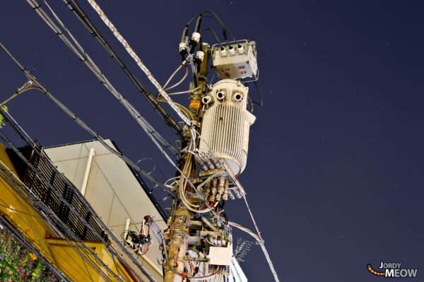 Mysterious advanced machine with multiple mechanical arms, set against night sky backdrop.