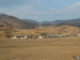 North Korean village surrounded by mountains, fields, and vegetation in a rugged landscape.