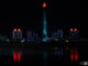 Pyongyang skyline at night with illuminated buildings and tower reflecting in still waters.