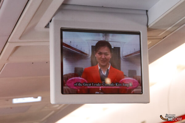 Inside a North Korean airplane cabin with display showing discussion on Kim Jong-il.