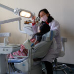 Dentist examining childs teeth in well-equipped Pyongyang dental office, showcasing professional care.