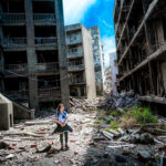 Exploring Gunkanjima: A lone explorer amidst haunting urban decay in Nagasaki, Japan.