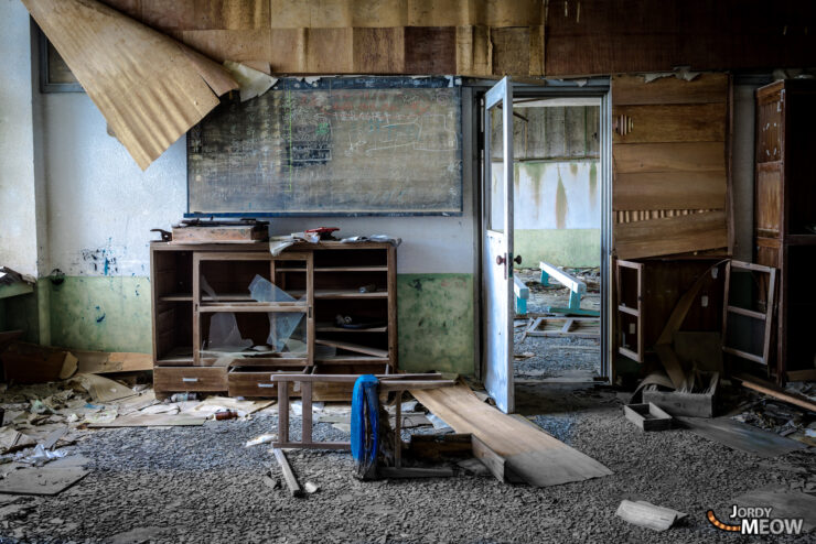 Abandoned classroom on Gunkanjima Island: decaying furniture, haunting atmosphere of forgotten mining community.