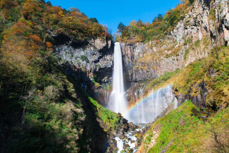 Enchanting autumn waterfall with rainbow and vibrant foliage, creating a mesmerizing display of beauty.