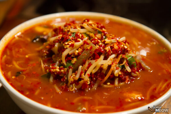 Savory cheese stew with rich broth, spices, and melted cheese in a bowl.