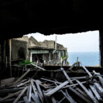 Exploring abandoned Gunkanjima Island apartments: a scene of desolation against a serene sea.