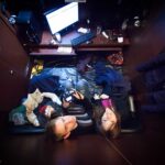 Restful intimacy in cluttered bedroom with sleeping couple, highlighting privacy and exhaustion.