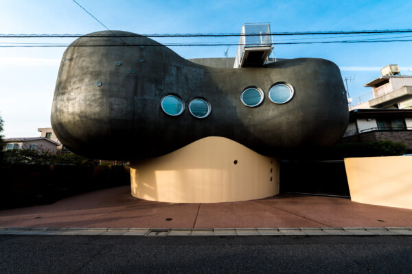 Whimsical sculpture in Tokyo city with circular openings, contrasting against clear blue sky.