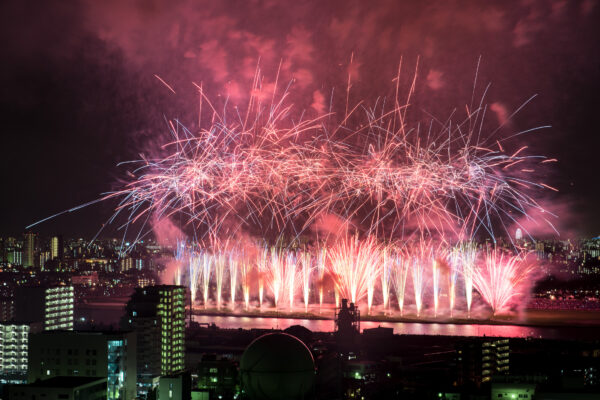 Vibrant fireworks light up city skyline in spectacular display over water.