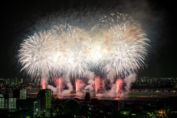 City skyline illuminated by vibrant white, gold, and red fireworks display.