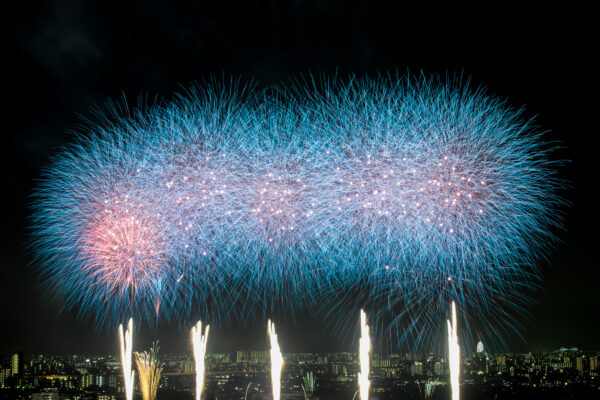 Vibrant fireworks illuminate city skyline in dazzling display of colors, shapes, and celebration.