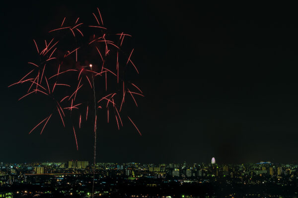 Spectacular fireworks display over city skyline at night, vibrant red and orange bursts.