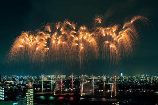 Cityscape fireworks illuminate the night sky with golden bursts over a bustling city.