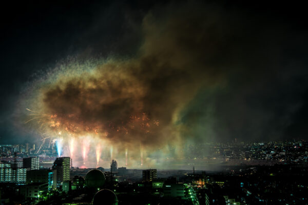 Spectacular fireworks show lights up city skyline in vibrant orange and yellow bursts.