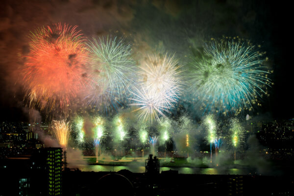 Dazzling fireworks over city skyline reflecting in dark waters, creating vibrant celebration.