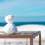 Enchanting Tottori Sand Dunes landscape with a whimsical snowman and serene ocean view.