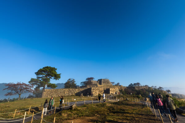 Historic Takeda Castle in Japan with impressive stone walls and towers overlooking lush greenery.