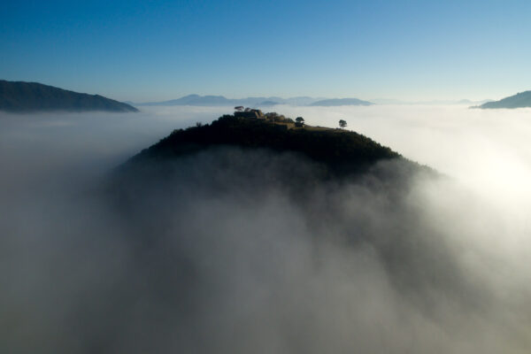 Takeda Castle shrouded in mist atop lush hill, embodying Japans rich history and culture.