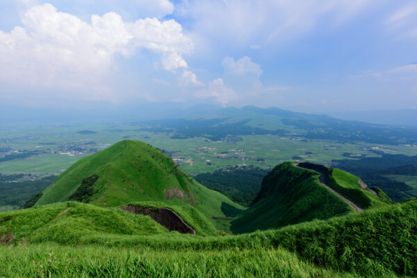 Scenic Aso Valley mountain road with lush green hills and majestic mountains view.