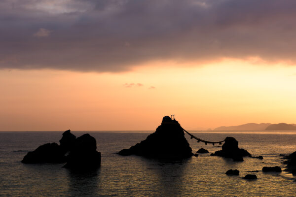 Sunrise at Meoto Iwa, Japan: Majestic rocks connected by torii gate in tranquil waters.