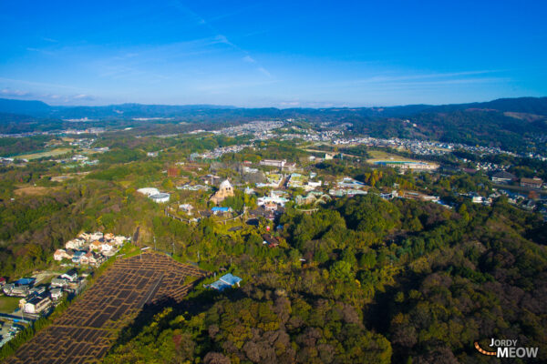 Aerial view of abandoned Nara Dreamland theme park with rusting roller coasters and lush forest.