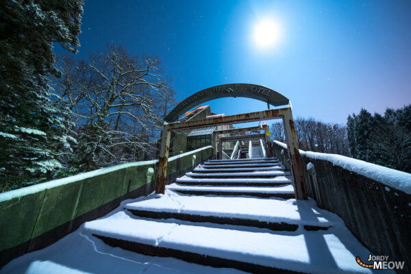 Abandoned Japanese hotel in snowy landscape, exuding haunting beauty and decay.