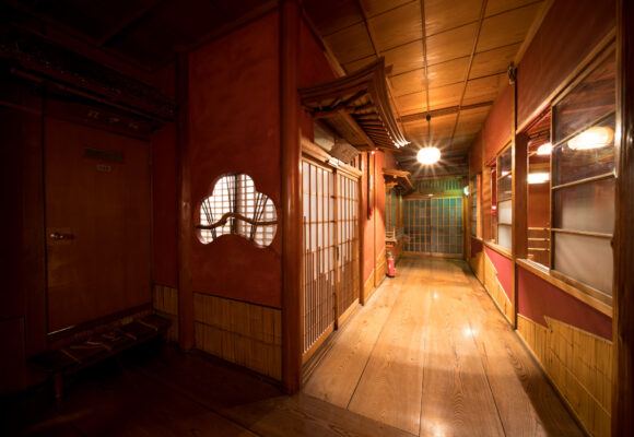 Cozy Japanese inn hallway with wooden floors, paper doors, lanterns, and warm ambiance.