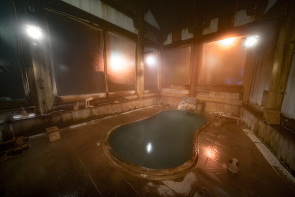 Tranquil onsen retreat in historic Kanaguya Ryokan, featuring cozy hot spring bath and wooden decor.