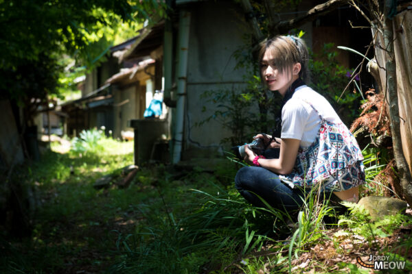 Exploring abandoned loggers village in Minobu Town, Yamanashi: woman amidst overgrown ruins.