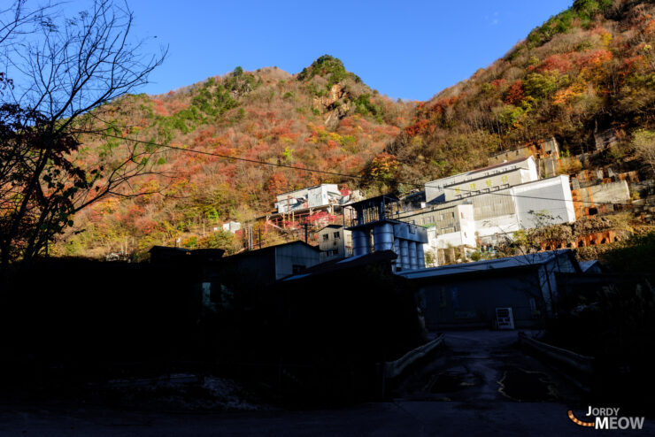 Exploring abandoned Nichitsu Mine in Saitama, Japan: industrial ruins against scenic mountains at sunset.