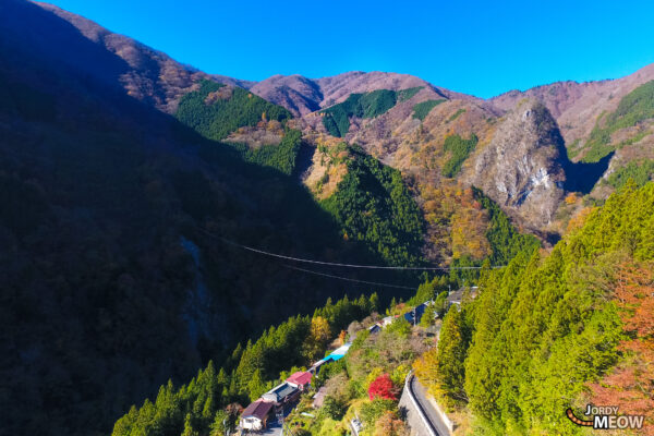 Autumn village in Kanto, Japan with vibrant foliage, rugged cliffs, and lush forests.