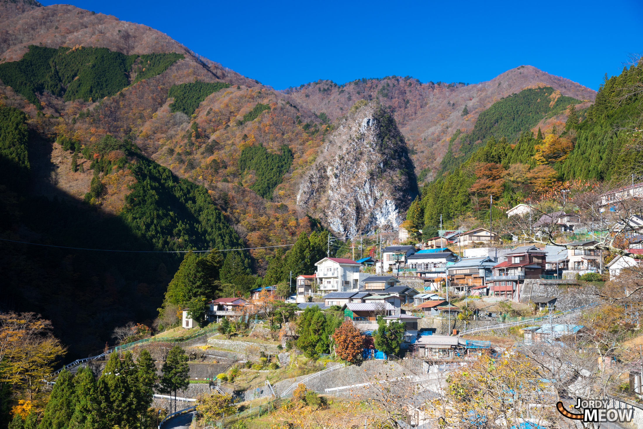 Inamura Rock: Majestic autumn landscape with vibrant foliage and peaceful village in Japan.