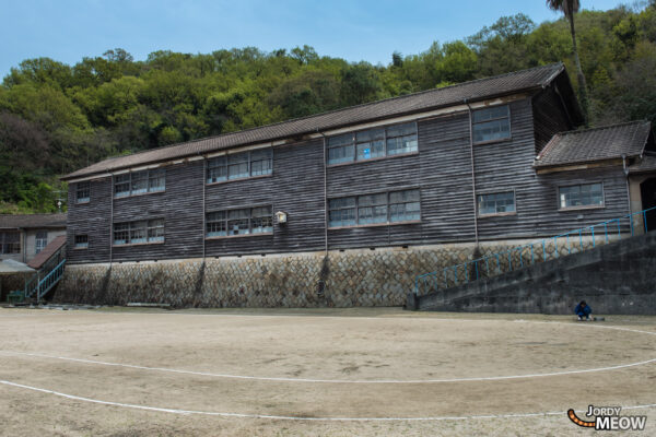 Tranquil village on Manabe-shima Island with historic school, Buddhist temple, and illustrated book.