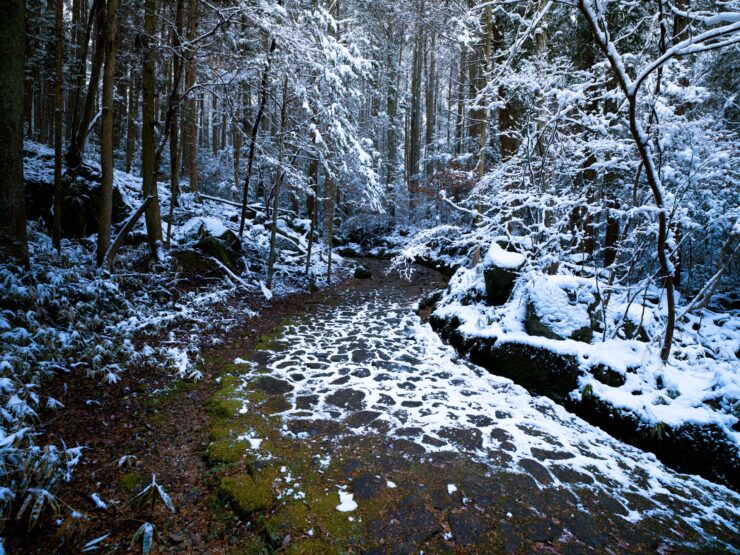 Snowy Japanese village path by frozen stream