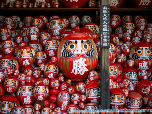 Iconic red Daruma dolls, symbols of perseverance.