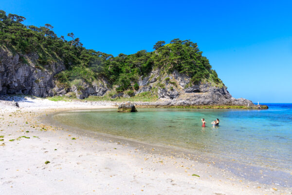 Shikinejimas turquoise waters, pristine beach, towering cliffs.