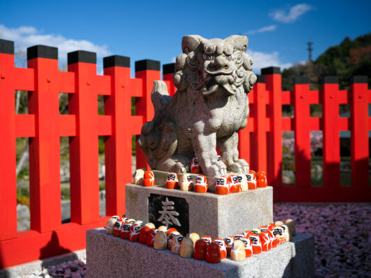 Traditional stone komainu lion statue with offerings