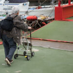 Elderly walker-assisted marina navigation.