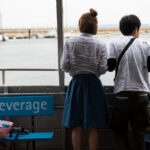 Tranquil harbor, Manabe-shima Island, couple admiring view.