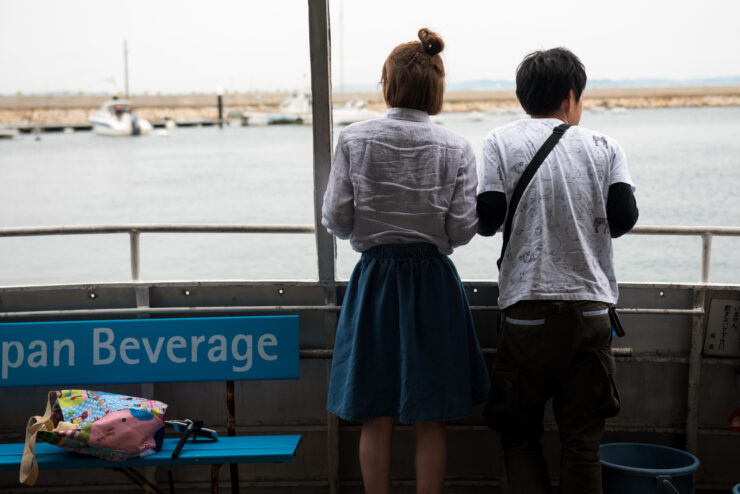 Tranquil harbor, Manabe-shima Island, couple admiring view.