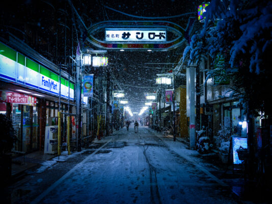 Illuminated snowy Japanese village street at night.