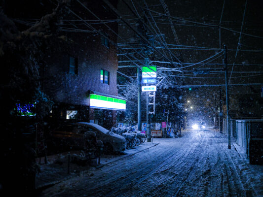 Snowy Tokyo street at night, illuminated storefronts