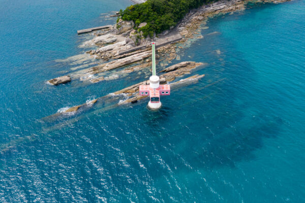 Breathtaking coastal gem: pink seaside building amidst turquoise waters.