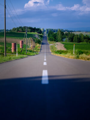 Scenic winding rural road through rolling green hills.